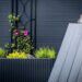 Rechthoekige cortenstaal plantenbakken op een modern terras met groene planten en bloemen.