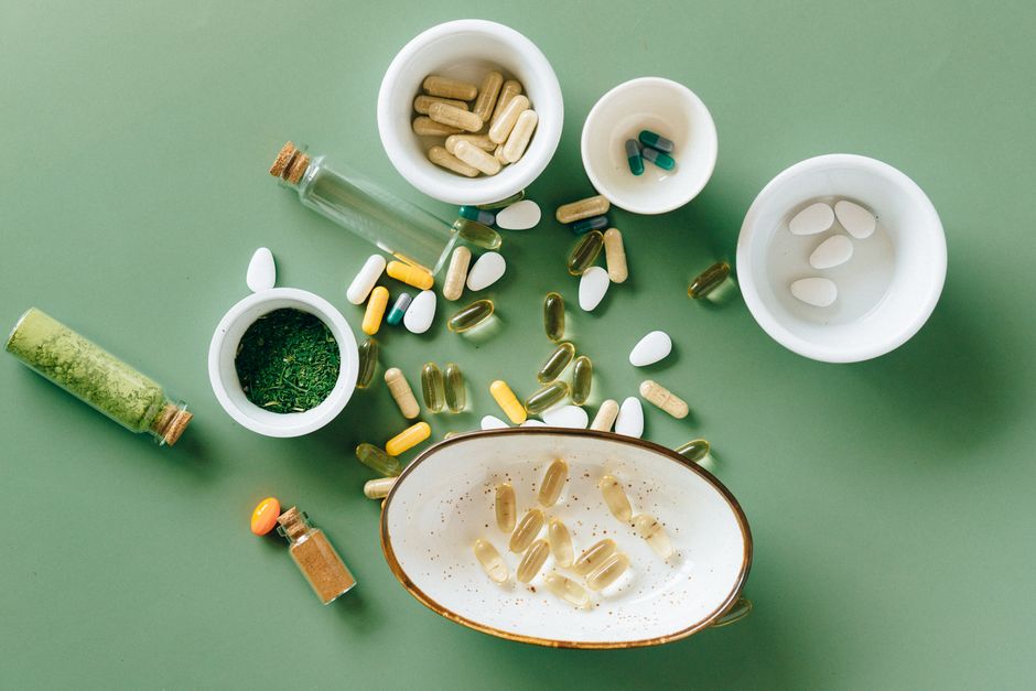 Een kleurrijke verzameling van vitamines en supplementen op een houten tafel, met innovatieve technologie in de achtergrond.
