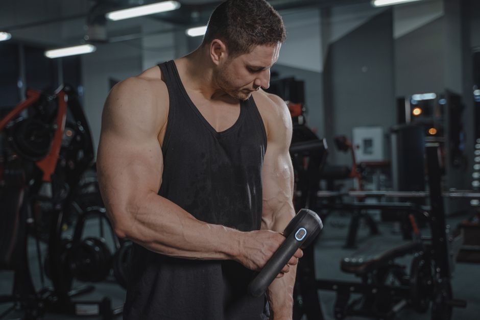 Een massagegun in gebruik voor spierpijn herstel na een intensieve training, geschikt voor sporters en fysiotherapeuten.